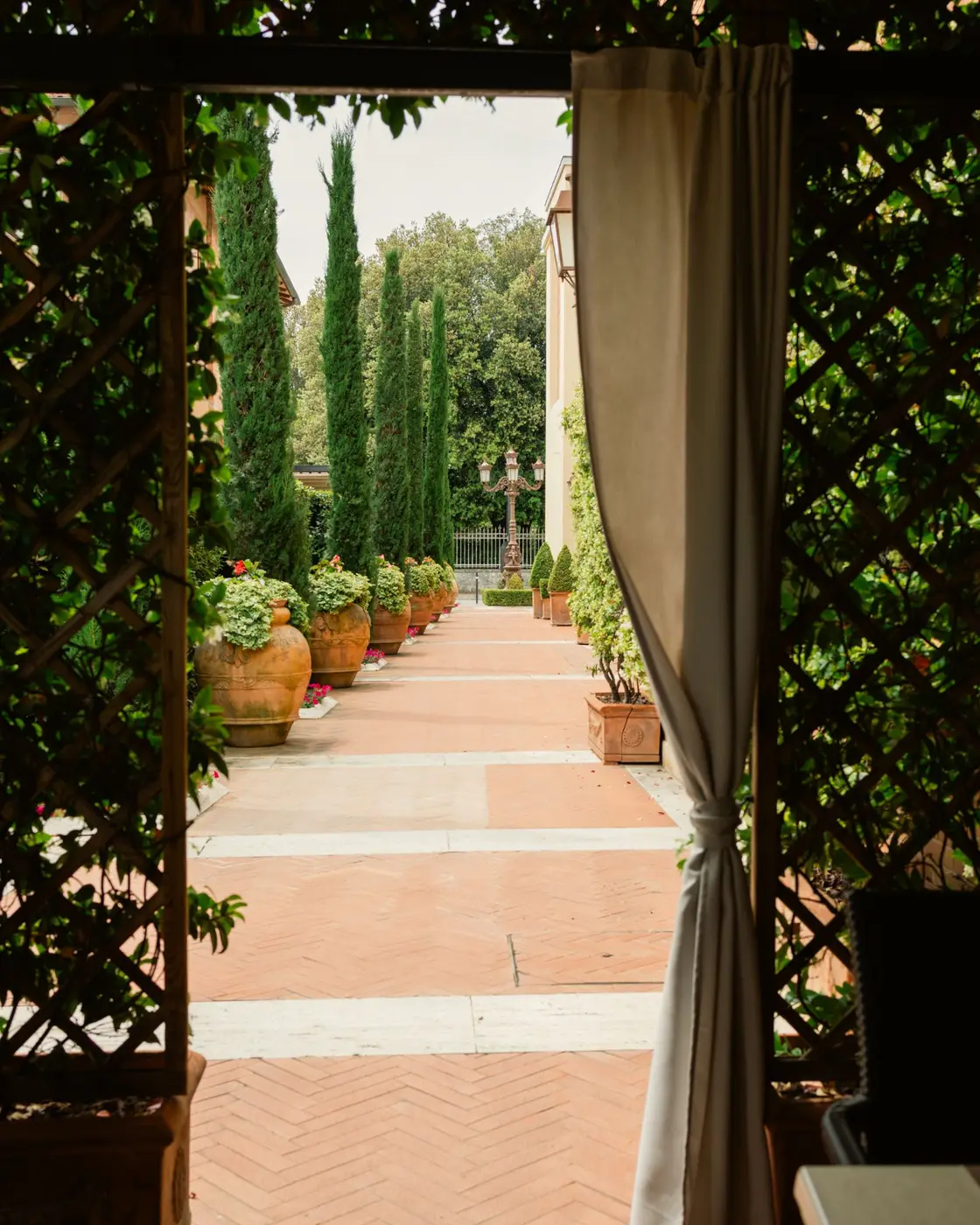 Il vialetto del giardino con cipressi e vasi di terracotta da la Piazzetta a Pienza